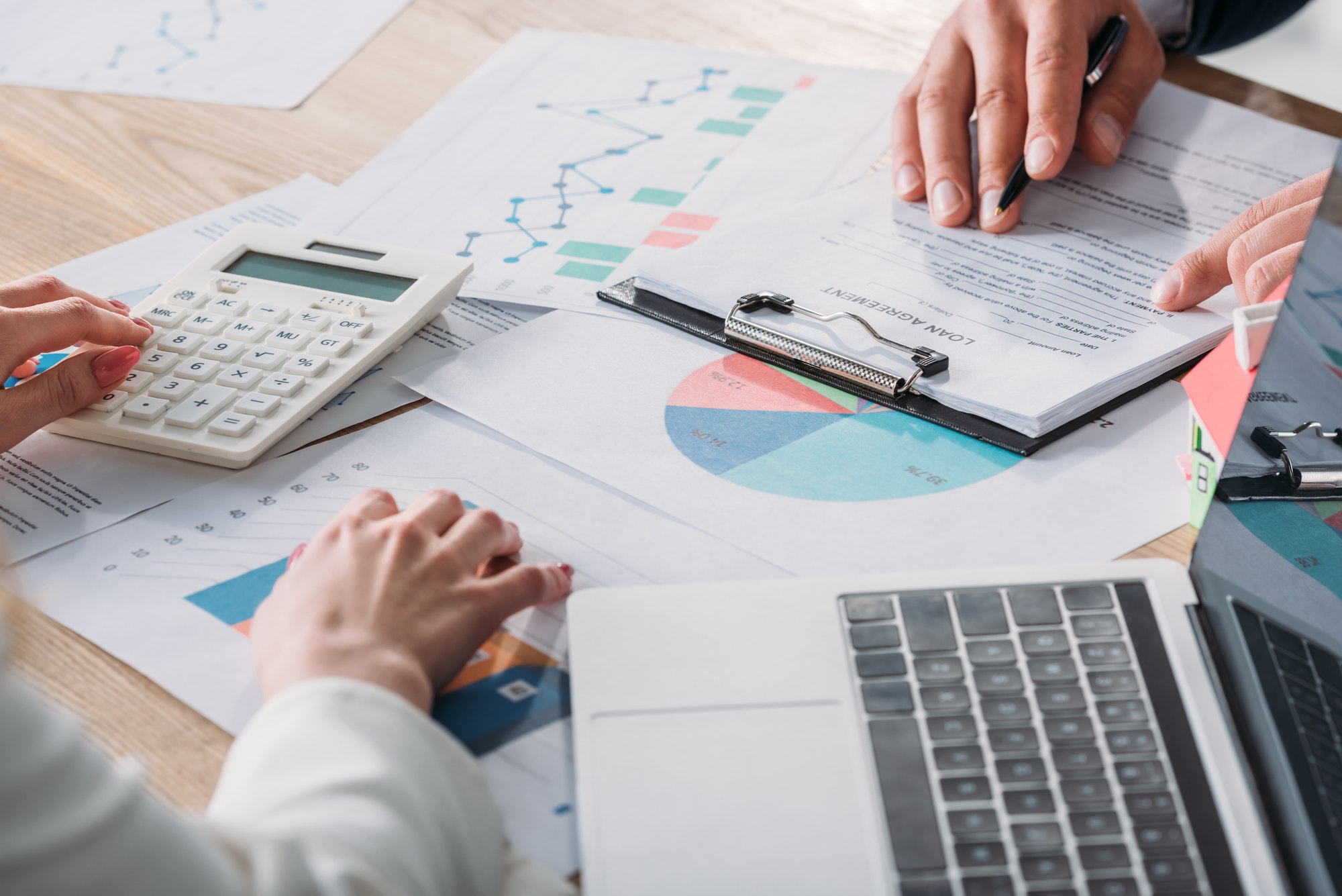 partial-view-of-man-studying-loan-agreement-and-businesswoman-using-calculator-while-sitting-at.jpg